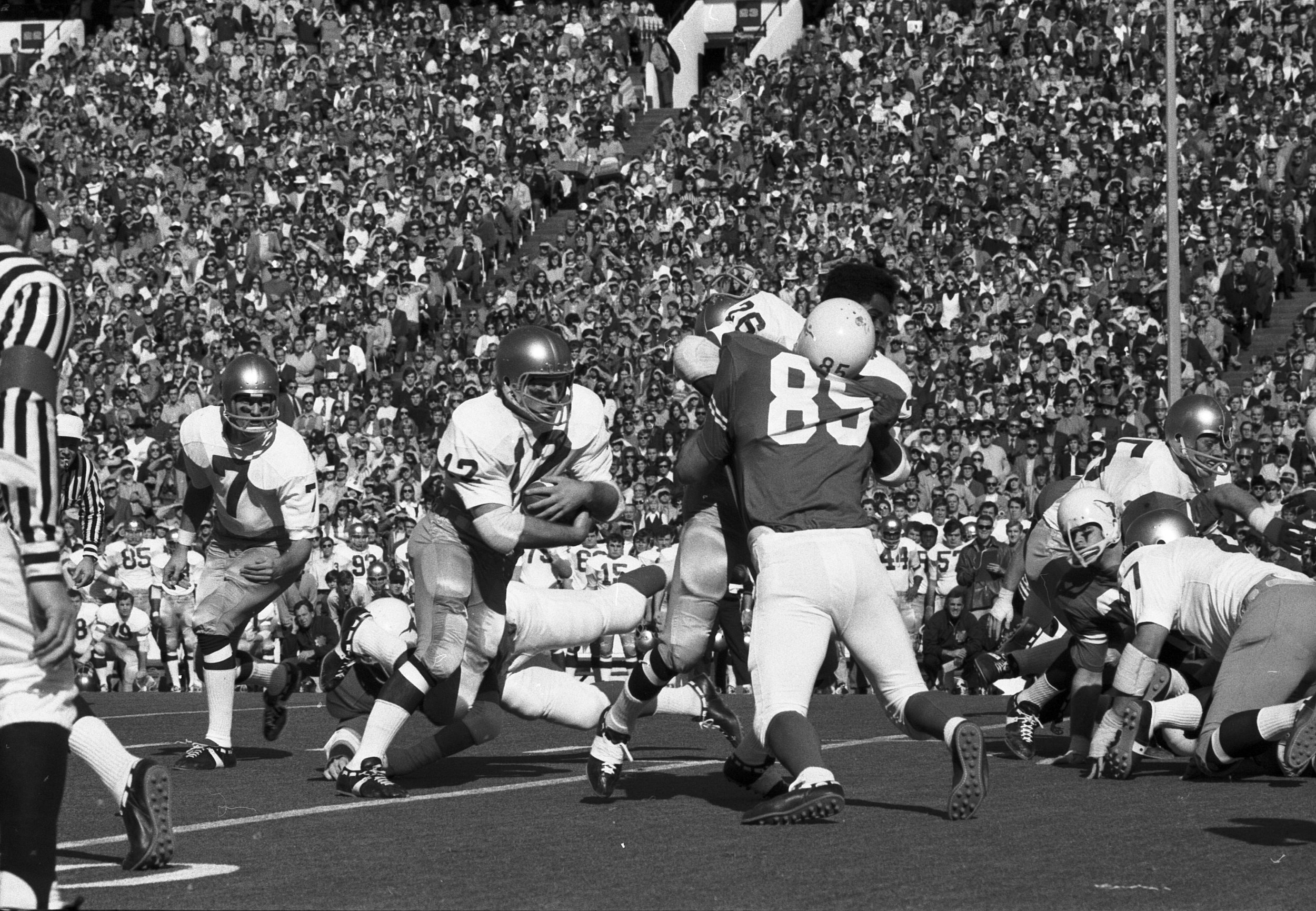 Stan Mauldin #85 knocks the helmet off the Notre Dame blocker. Joe Theisman is #7. Notre Dame Coach Ara Parseghian is squatting down on the Notre Dame sideline by number 44.