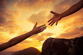 Two hands reaching out towards each other against a sunset backdrop, symbolizing connection and support.
